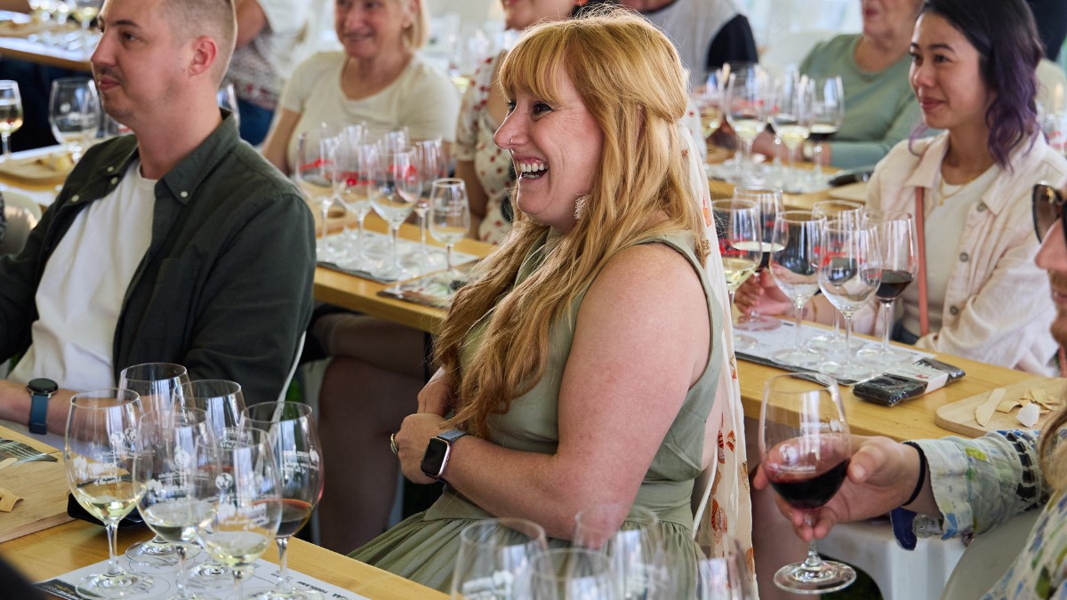people sitting at rows of tables with several wine glasses for tasting