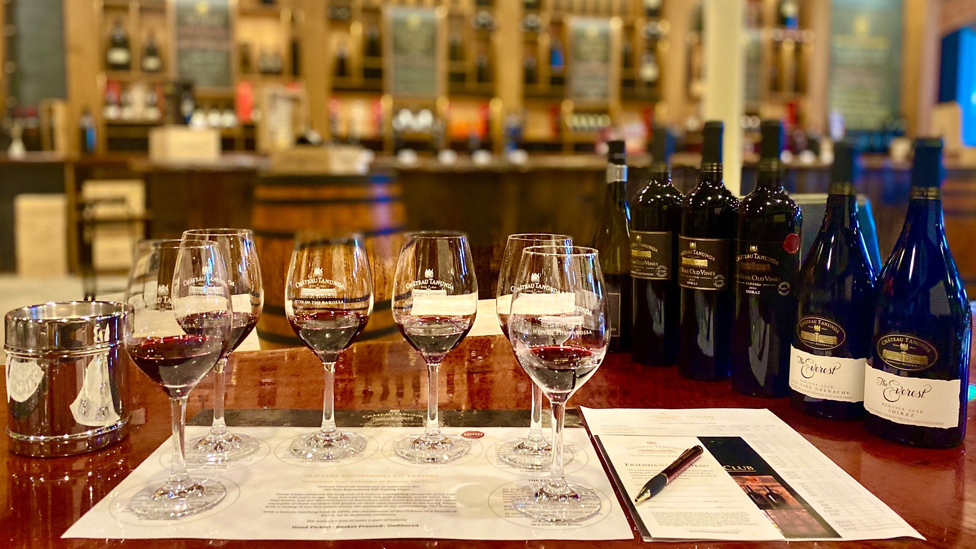 Glasses of red wine placed on a piece of paper next to bottles of wine.
