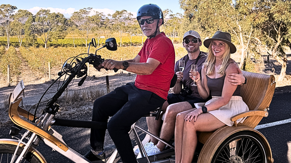 A man drives 2 wine drinkers around on an ebike